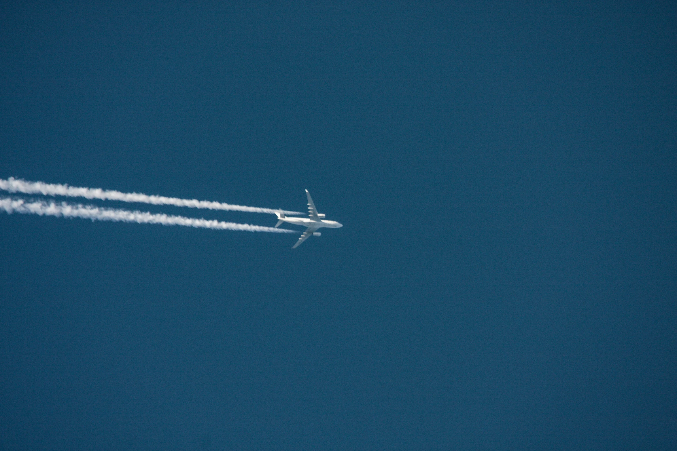 an airplane flying through the blue sky and leaving a trail