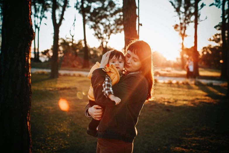 two adults and a child standing in the grass by a tree