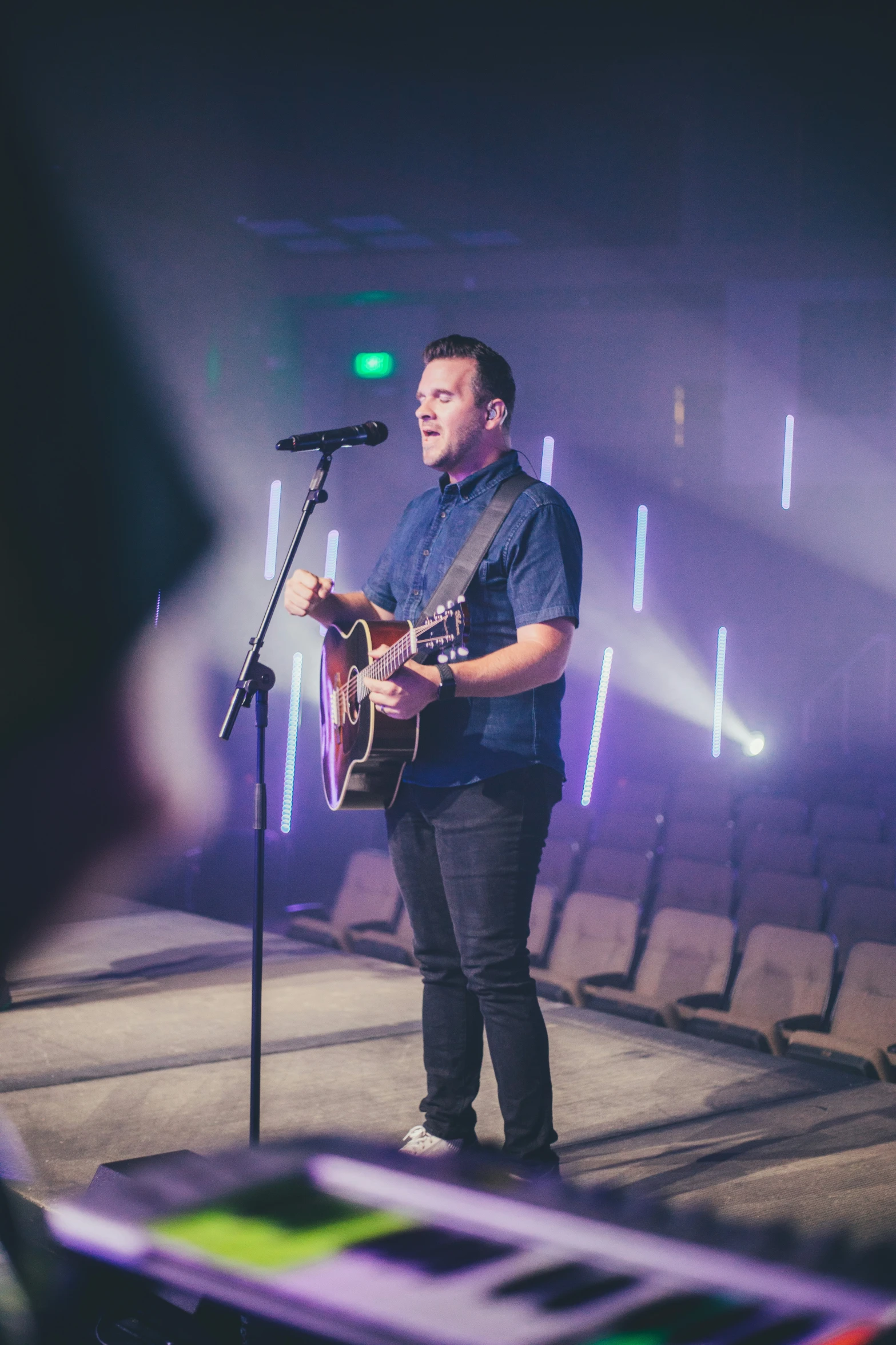 a man holding a guitar standing in front of a microphone