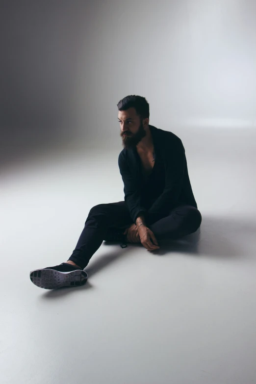 a man is sitting on the ground and staring away