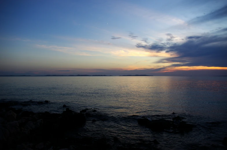 a sunset view of the ocean with some clouds