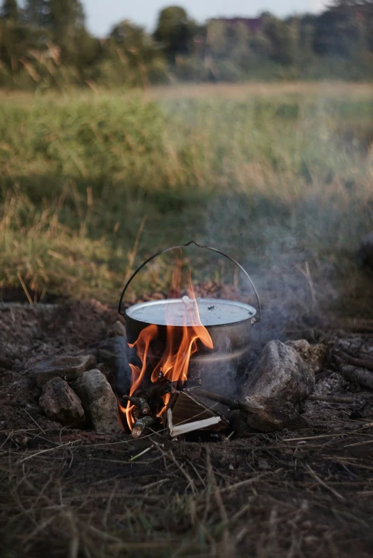 a pot sitting on top of a fire in the grass