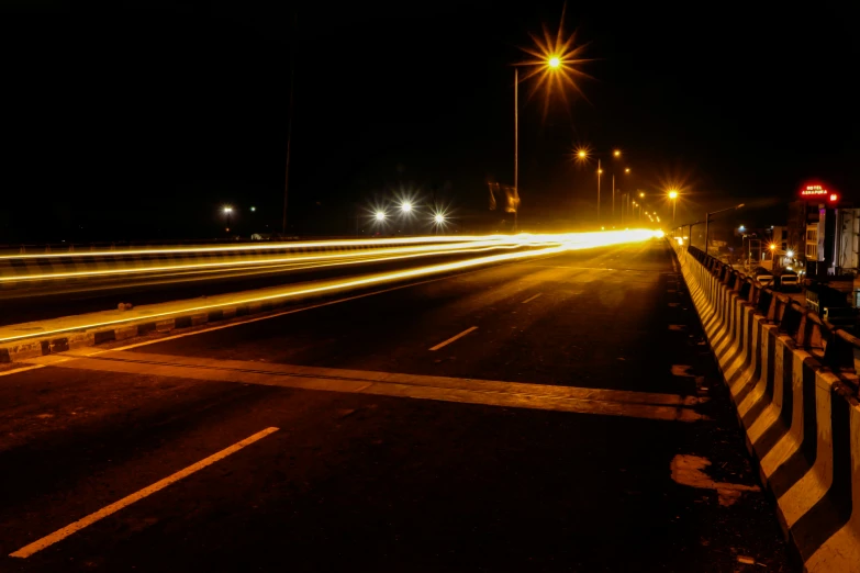 an empty street at night and bright lights at the end of the road