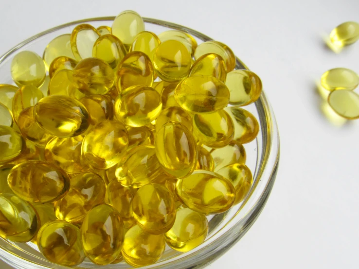 a bowl filled with yellow pills sitting on top of a table