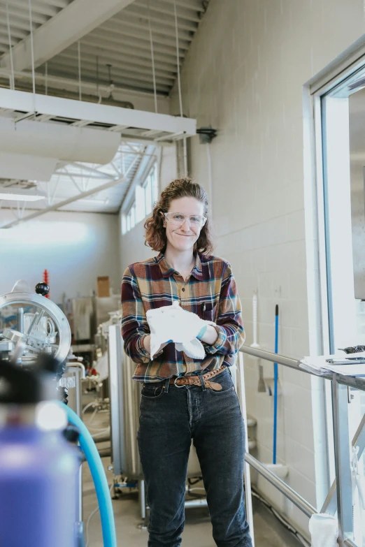 a woman standing outside of a factory holding a piece of paper