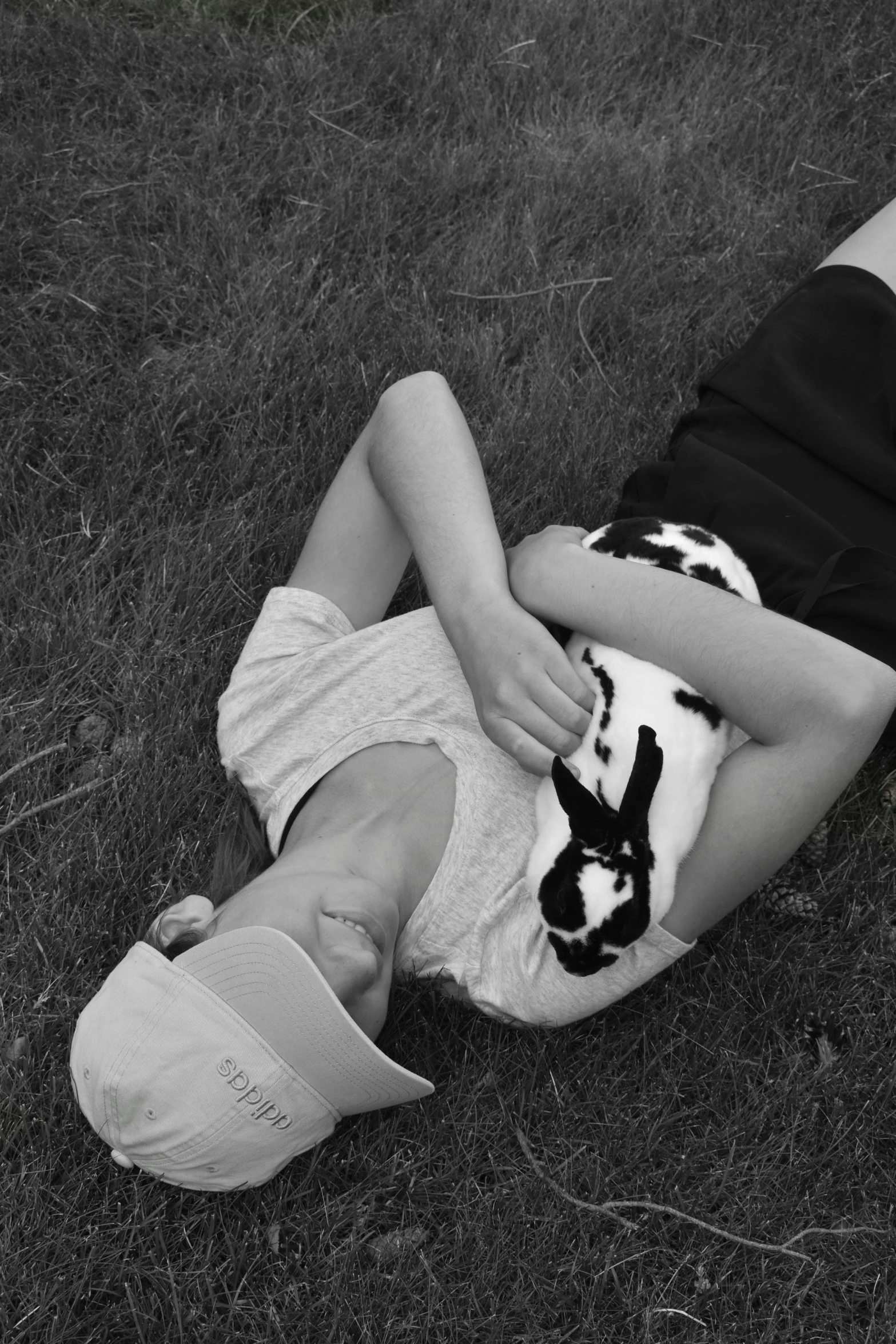 a small child holds a cat while lying on the grass