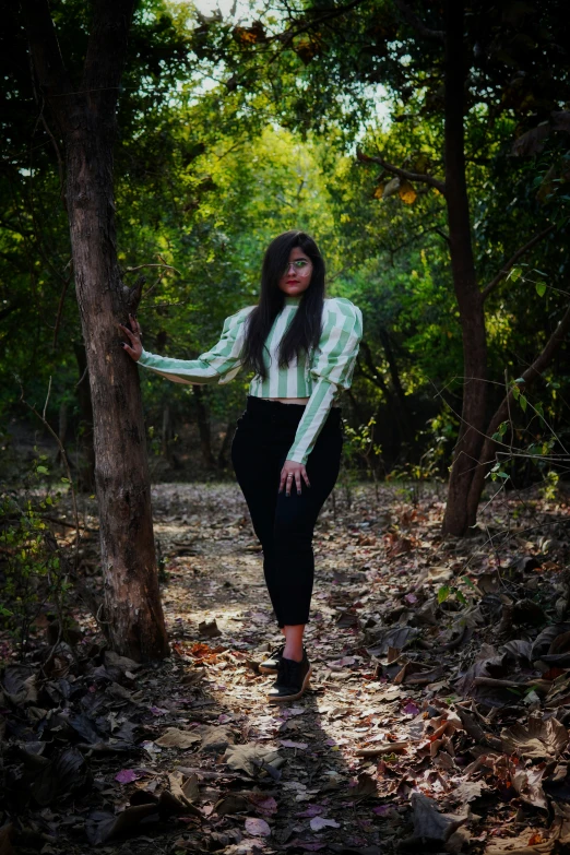 woman in black pants walking down a path by trees