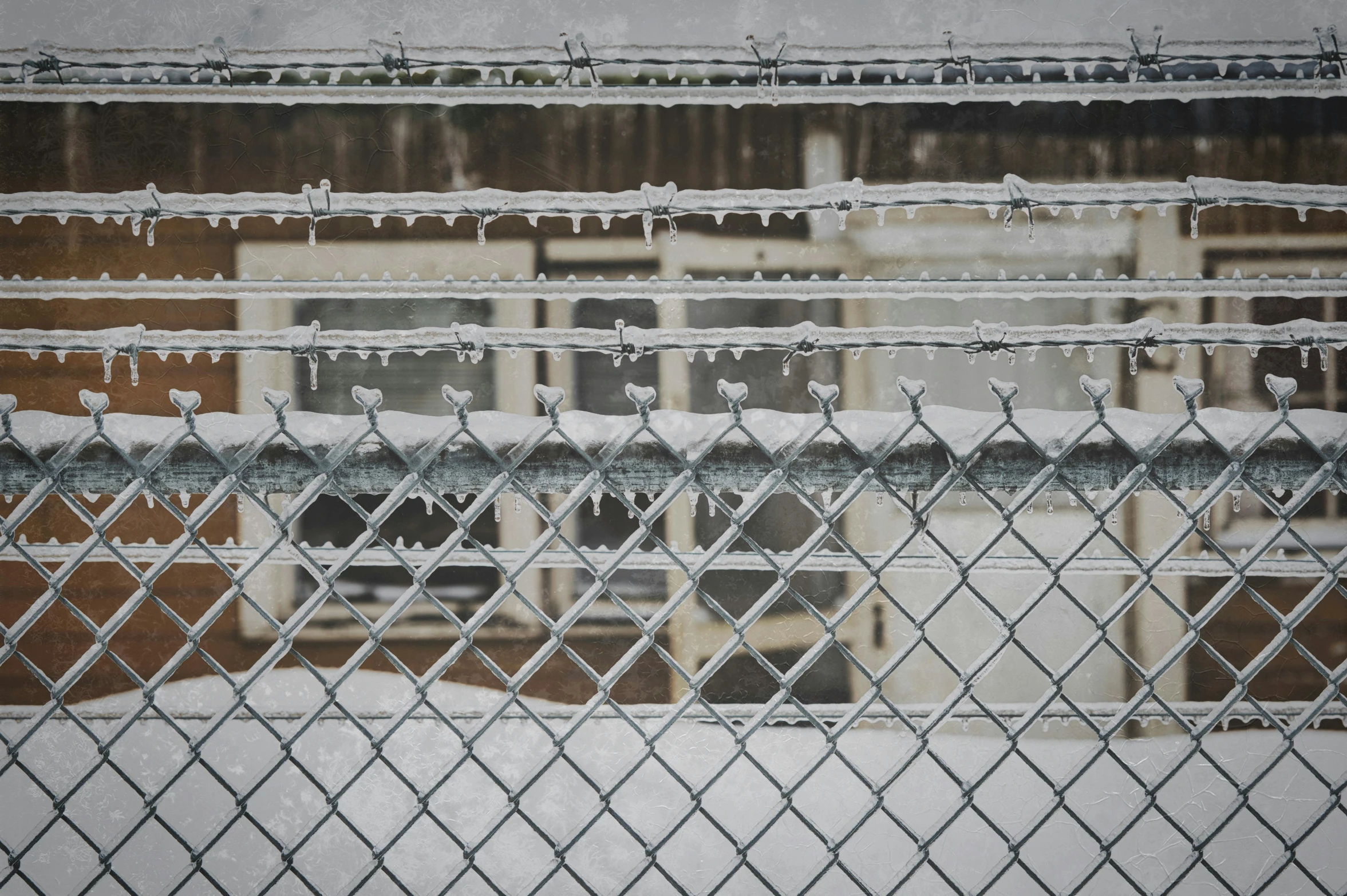 a fence with water droplets covering the fence and building in background