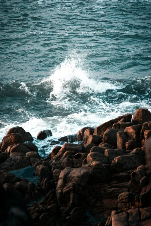 a person standing on a rocky beach near the water