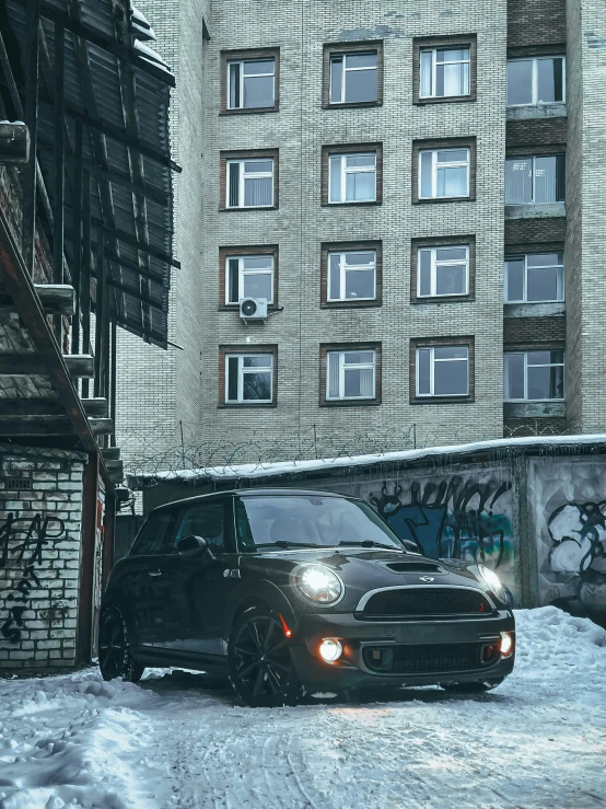 a black suv driving in the snow next to some buildings