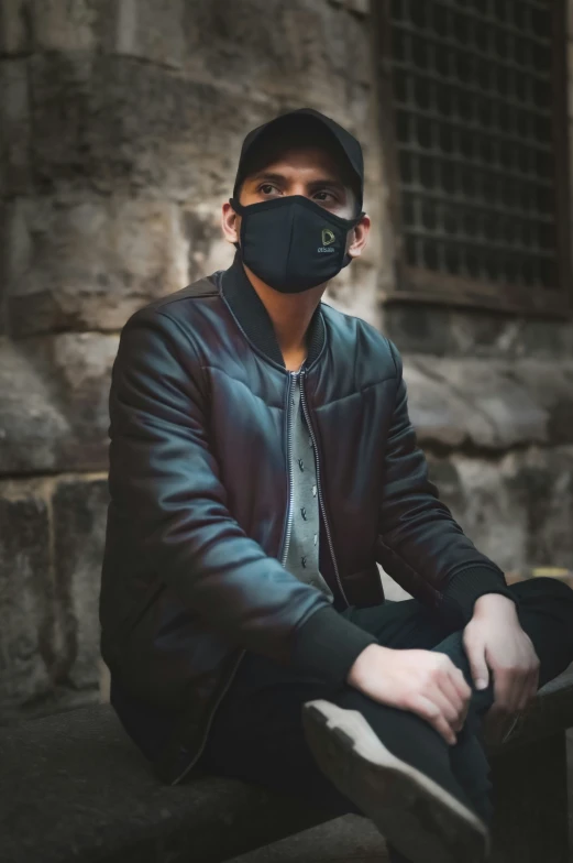 a man in a black jacket wearing a mask