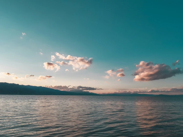 view from the side of a body of water as the sun sets