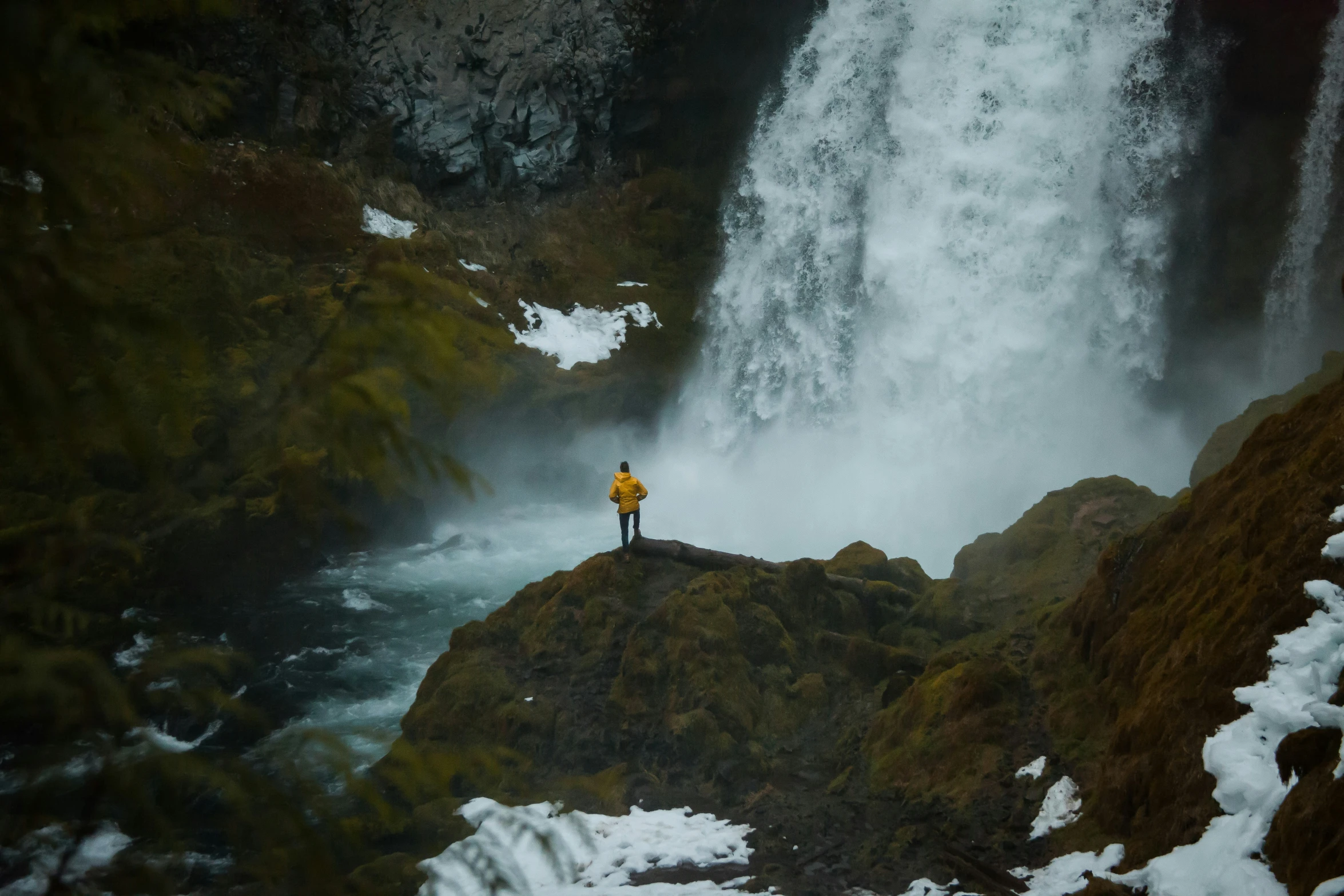 a man is standing on top of the rock next to a waterfall