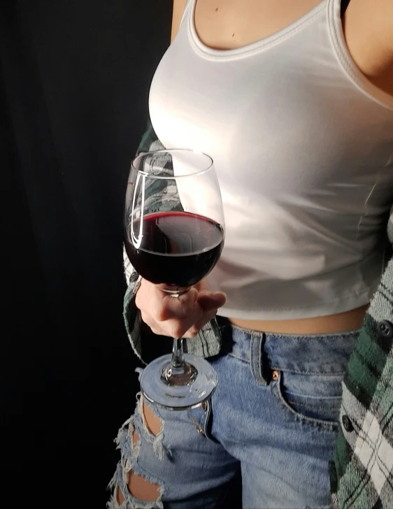 the woman is standing holding a glass of wine