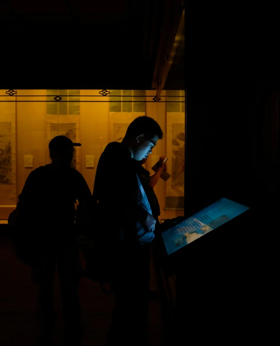 three people standing in the dark and looking at a screen