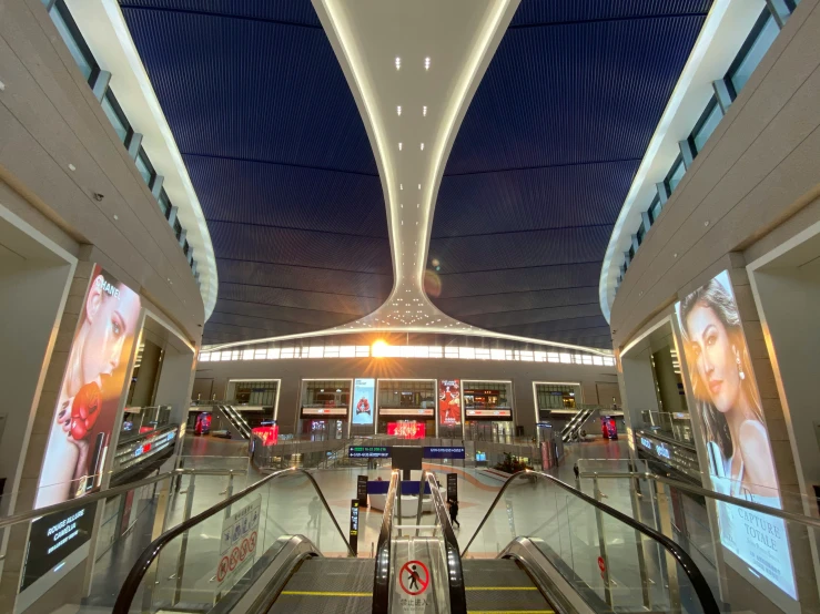 a large airplane terminal with several escalators and screens