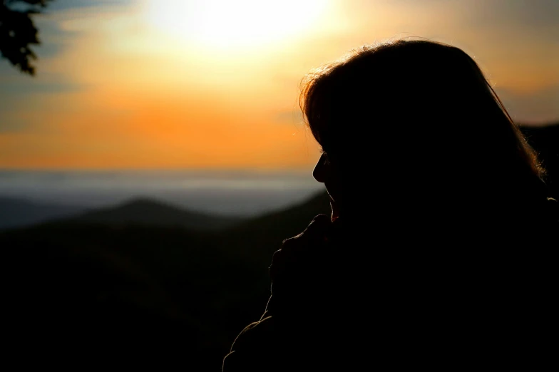 a woman is silhouetted against the sunset