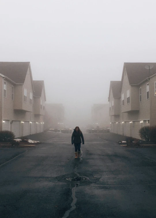 man walking down street in the middle of a foggy day