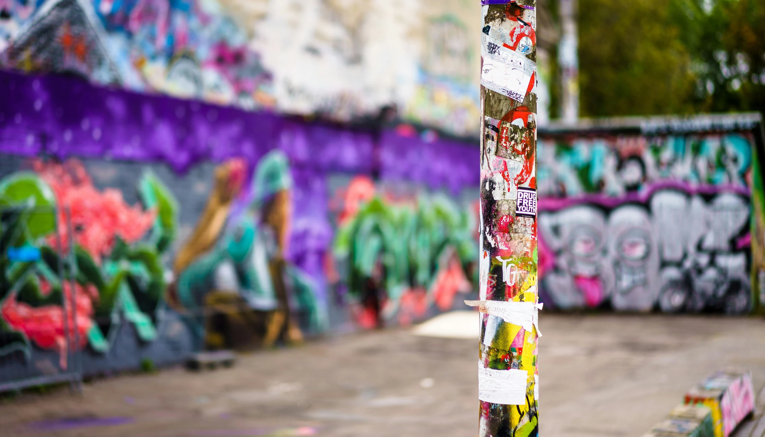 a pole in front of a colorful wall with graffiti