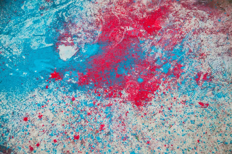 red and blue paint is on the ground next to a bottle