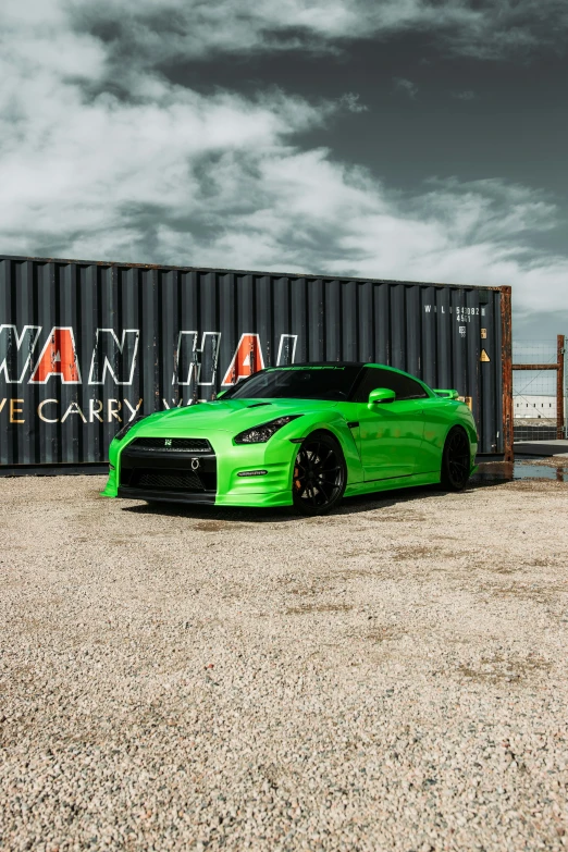 a green car parked in front of a cargo container