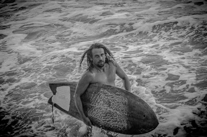 a woman walking in the water carrying a surfboard