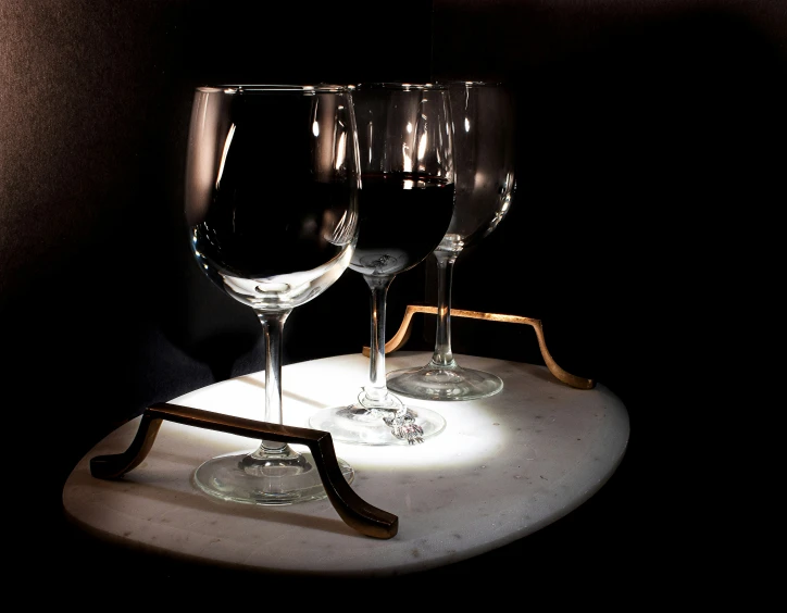 three wine glasses and a bottle sit on a table