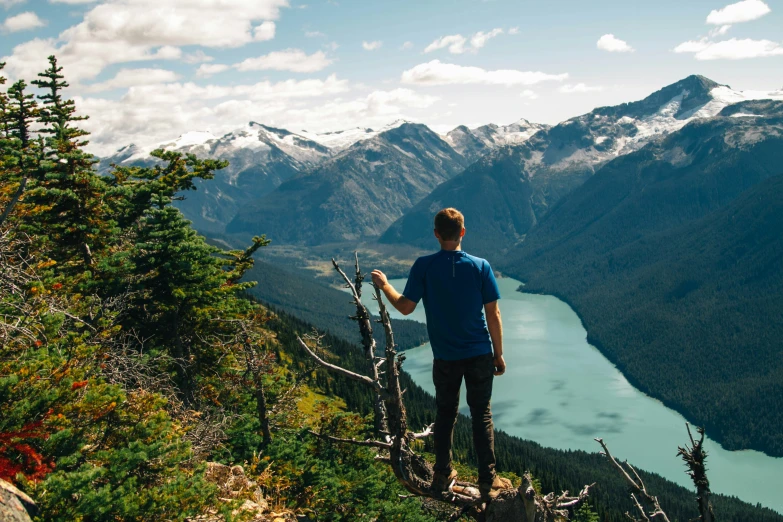 a man stands on top of a hill overlooking mountains and a lake