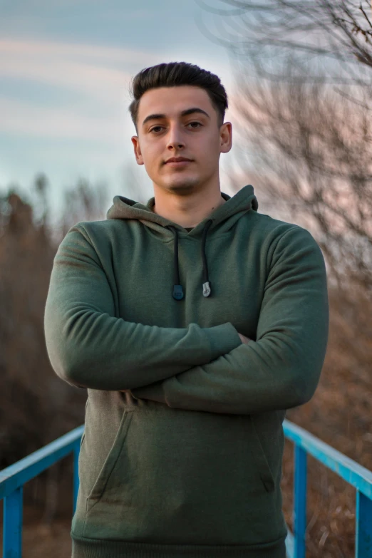 man with hands crossed standing outside on the balcony