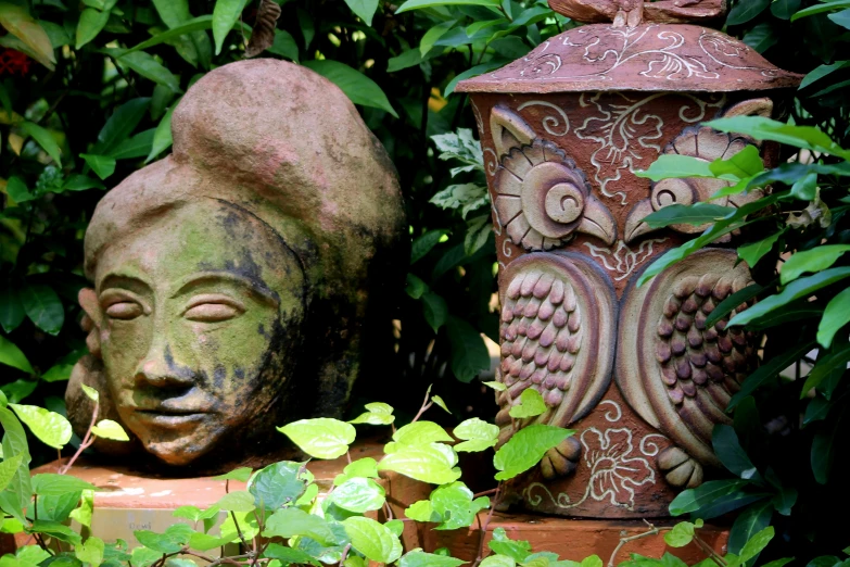 a couple of very cute stone statues by some plants