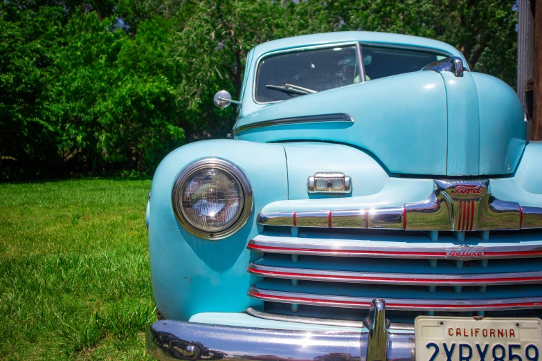 an old blue truck with chrome trim is parked in a field