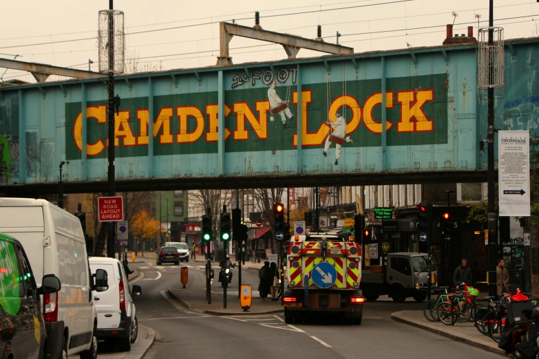 cars and trucks traveling under a bridge that says camden locks