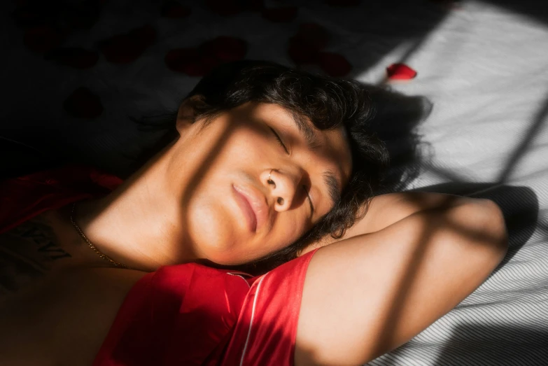 young woman laying down with eyes closed and a shadow cast on her body