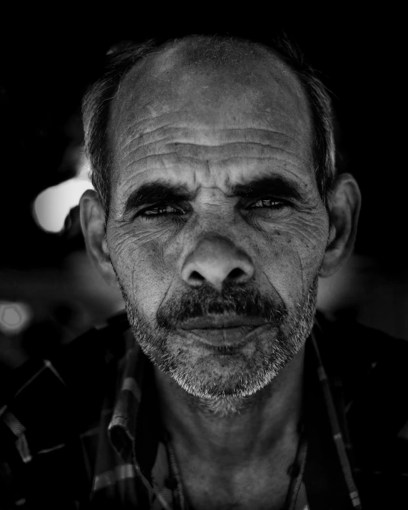 a man wearing a scarf and a checkered shirt stares at the camera