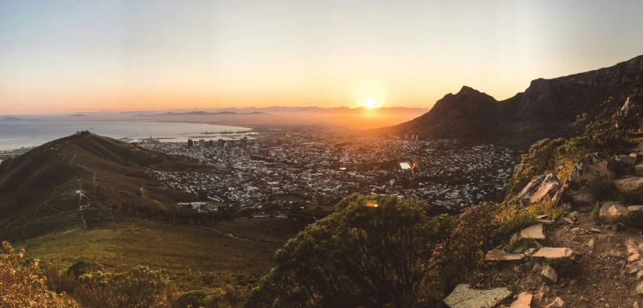 a sunset s with the sun rising over a city on top of a mountain