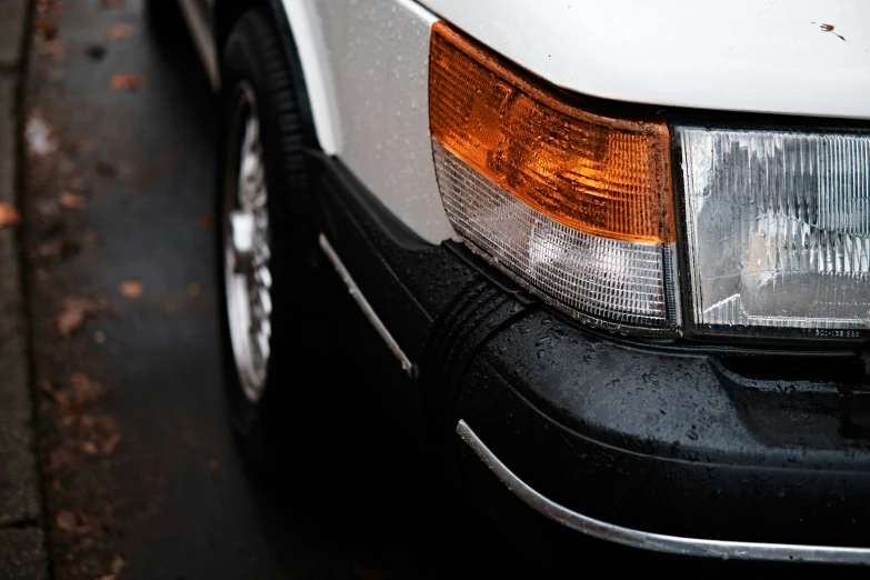 the front end of a white car parked next to a road