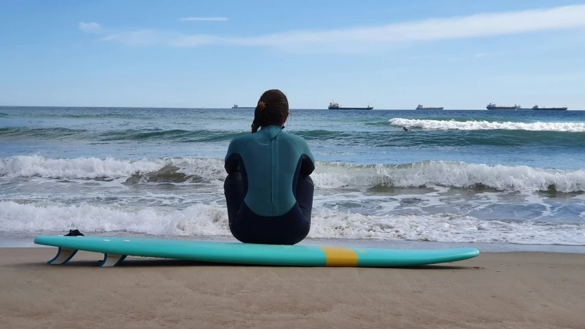 the surfer is sitting on a surfboard near the ocean