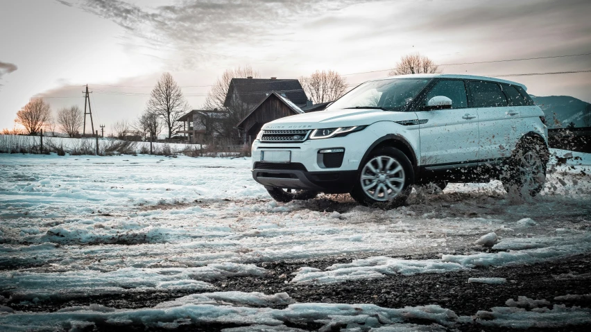 the white land rover in the snow in front of a house