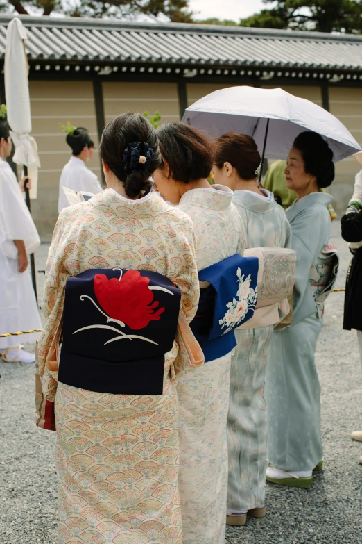 women in hanry holding umbrellas walking towards a building