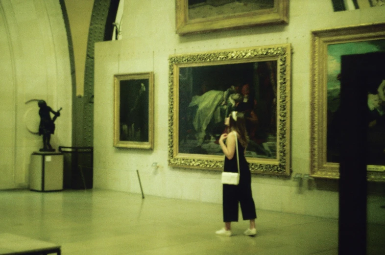 there is a woman taking a picture in front of some paintings