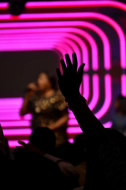 a silhouette of a hand holding their hands up at a concert