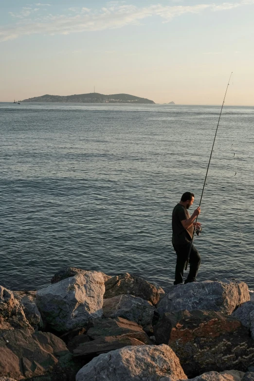 a man on a rocky shore holding a fishing rod
