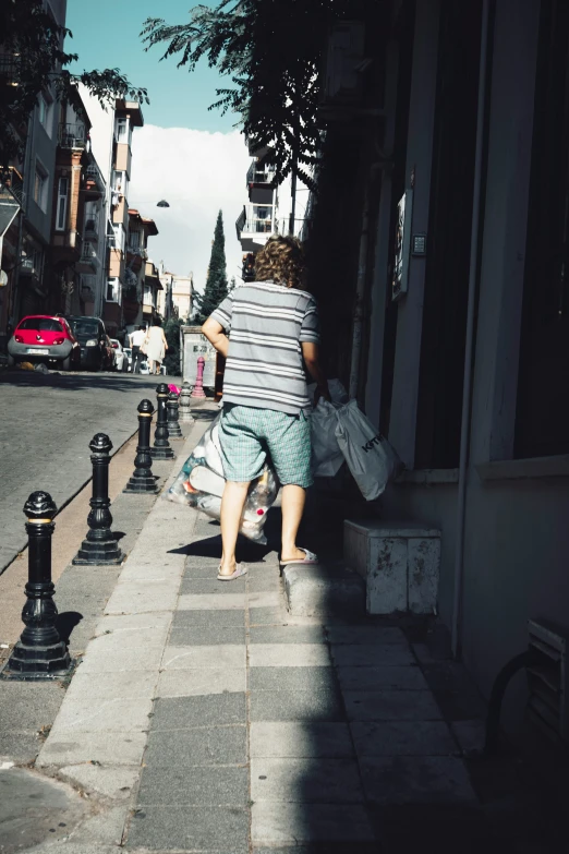 a person walking down the sidewalk while carrying some luggage