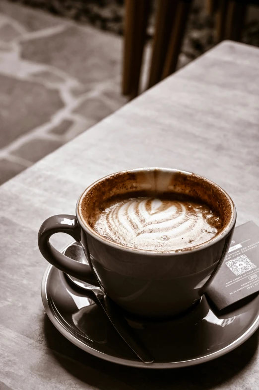 a cappuccino sits on a saucer and coffee bag