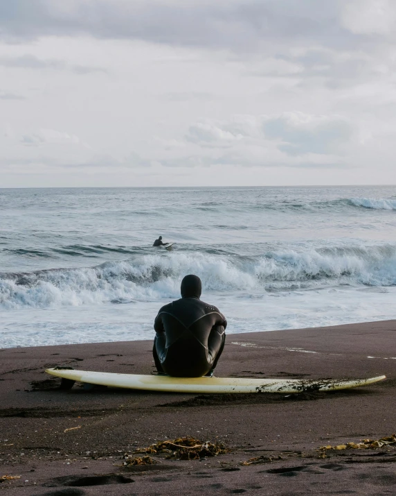 a person sitting on the beach looking at the waves