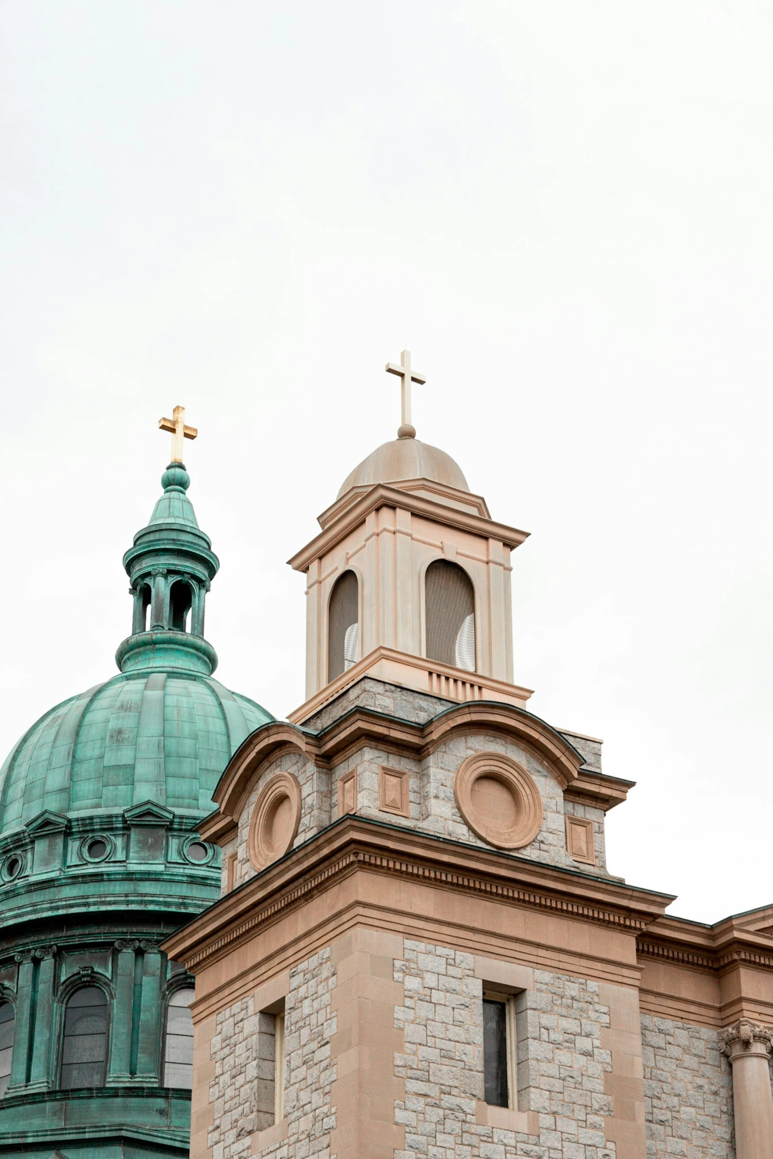 a stone building with green domes is under a white sky