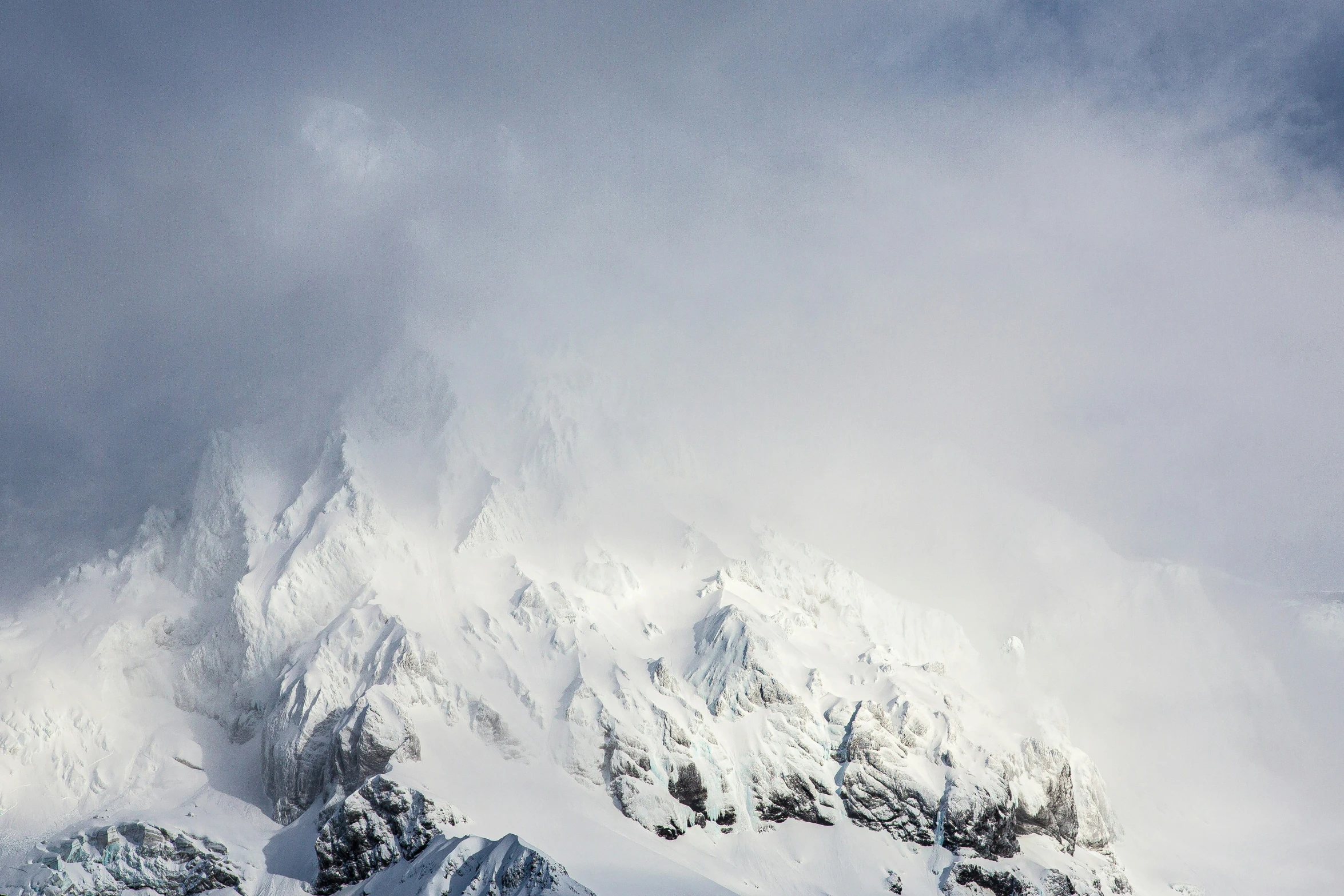 snow covered mountains are in the distance under a cloudy sky