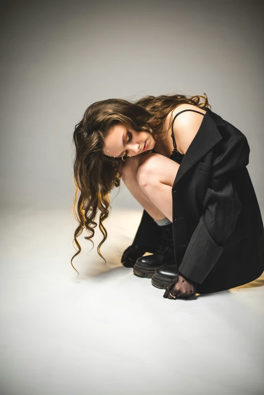 a woman in black dress kneeling on a white surface