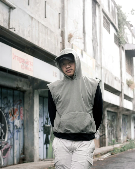 a man in white shorts and a grey hoodie standing in the street