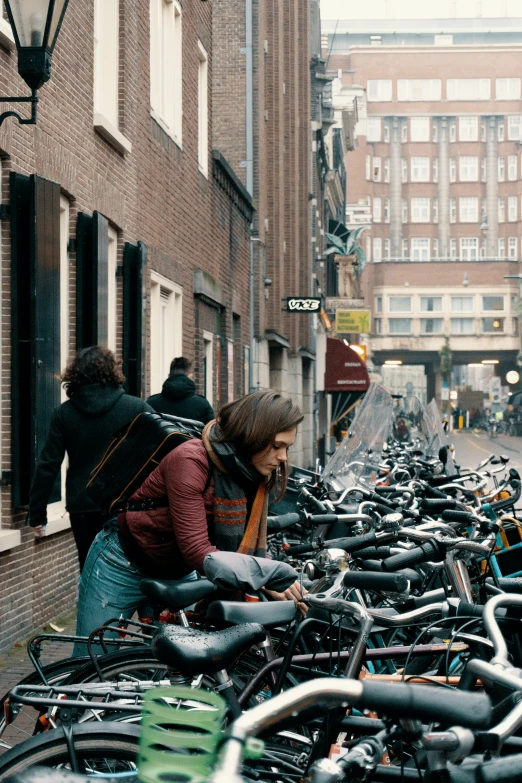 a woman standing next to a large group of parked bikes